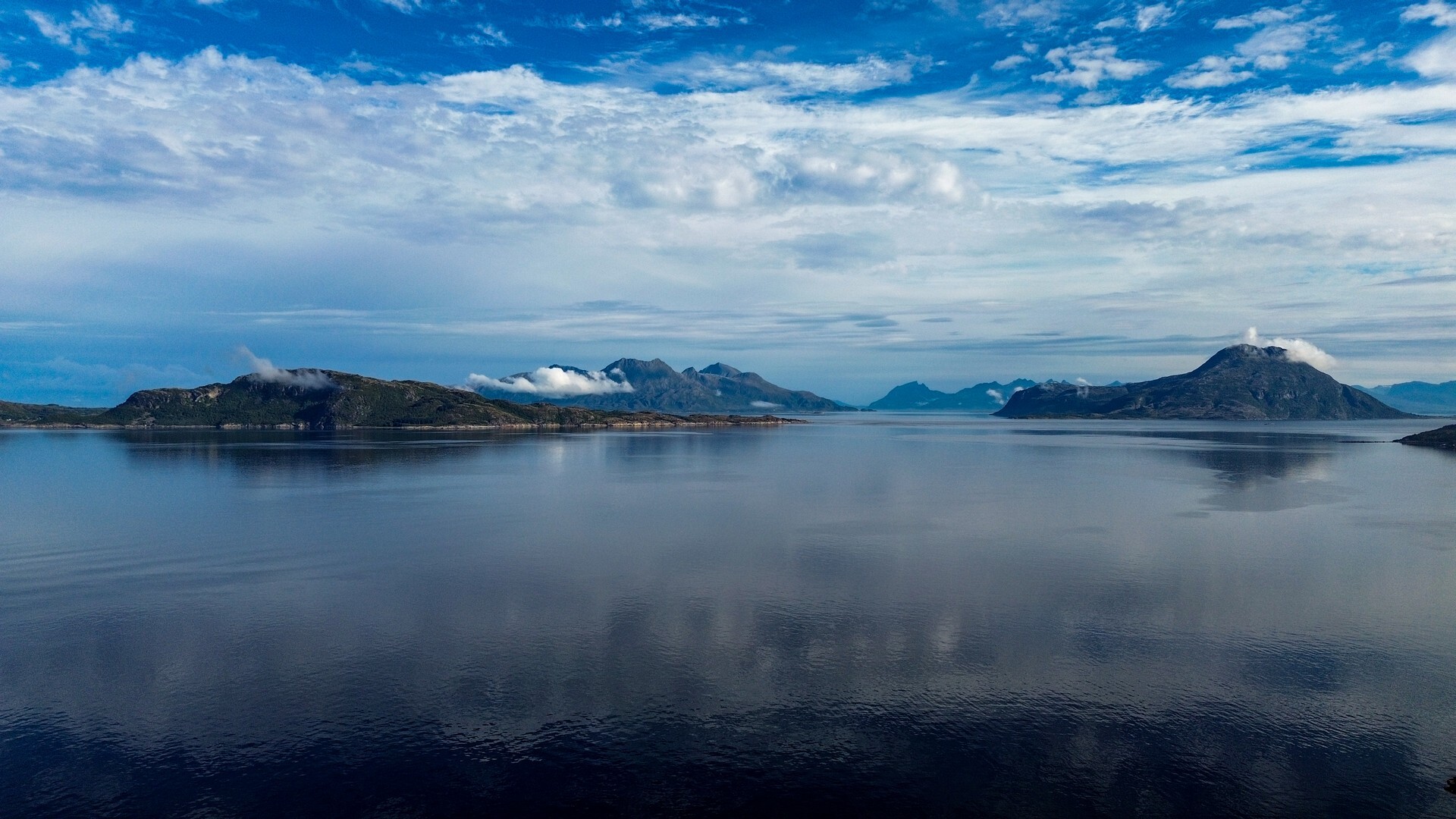 Spokojny fiord z górami i chmurami odbitymi w wodzie – widok z drona nad Fagervika